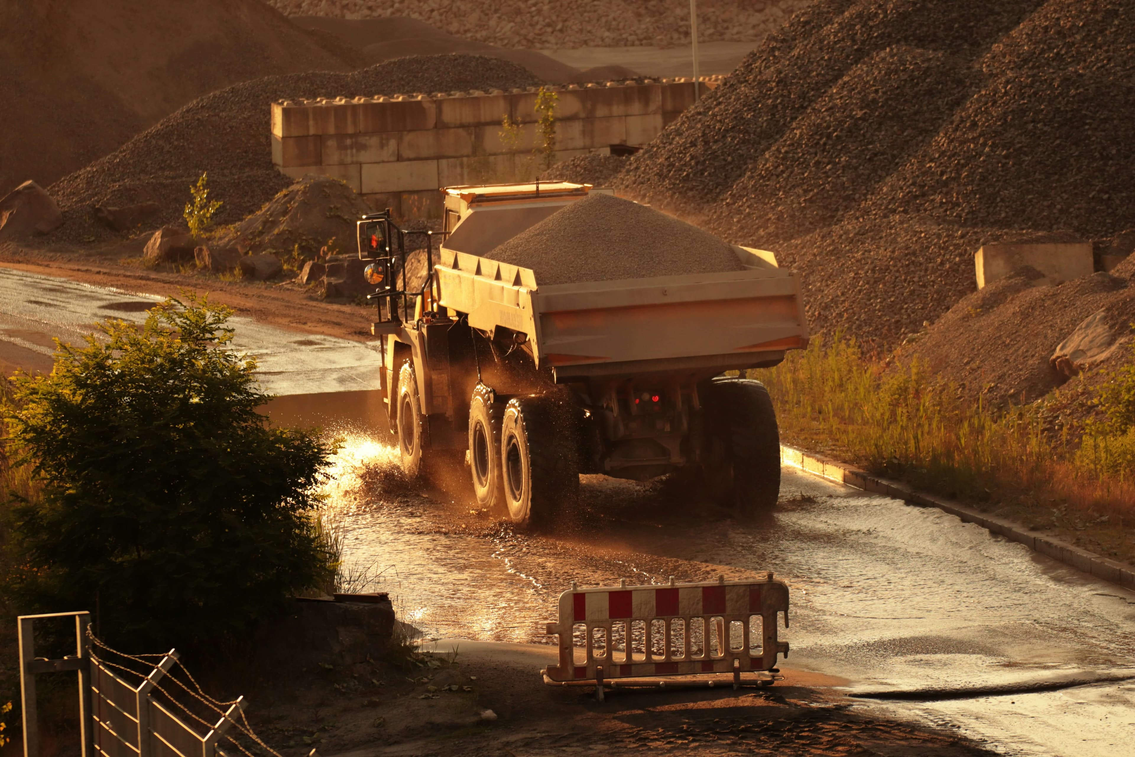 Dump truck driving towards a sunset